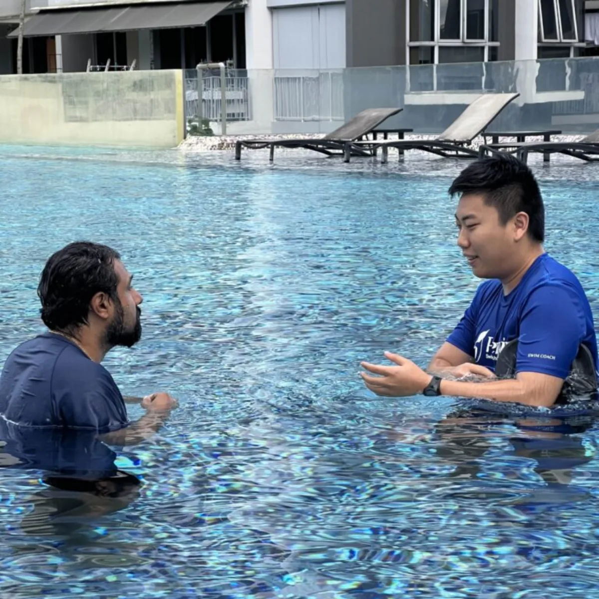 Penguin Swim School coach speaking with an adult learner during a private swimming lesson
