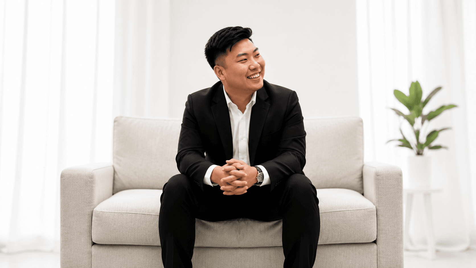 Rayner Teo seated on a light sofa in a bright living room